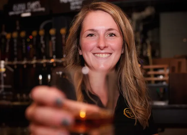 Woman handing glass of whiskey