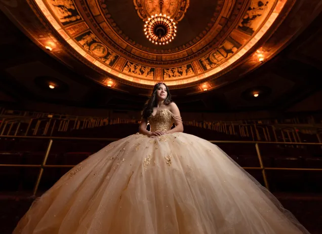 young woman in ball gown standing in a theater